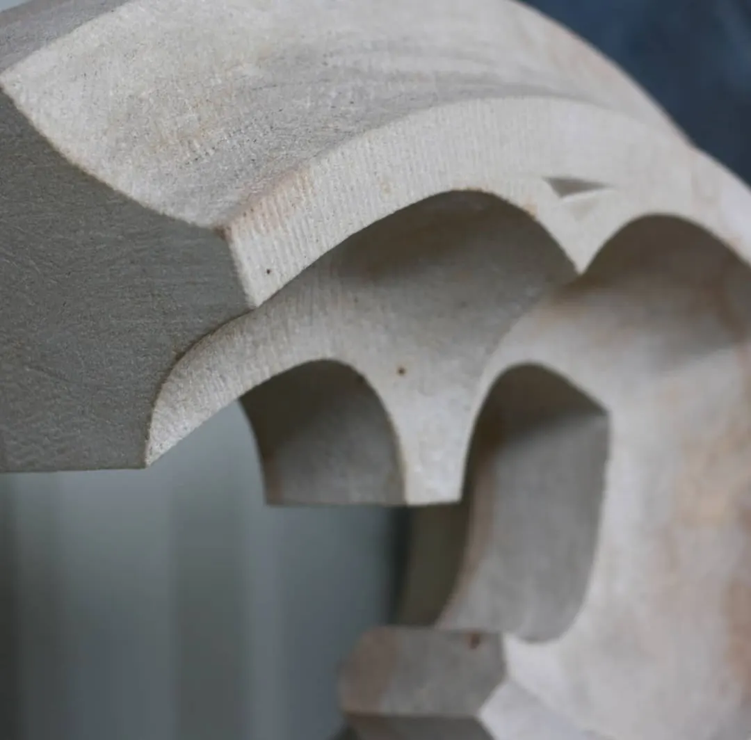 Detail einer Steinmetzarbeit aus hellem Sandstein mit gearbeiteten Bögen